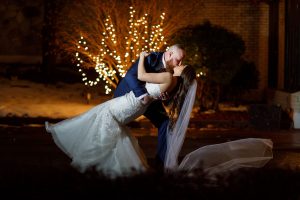 Bride dipping groom with twinkle lights in background