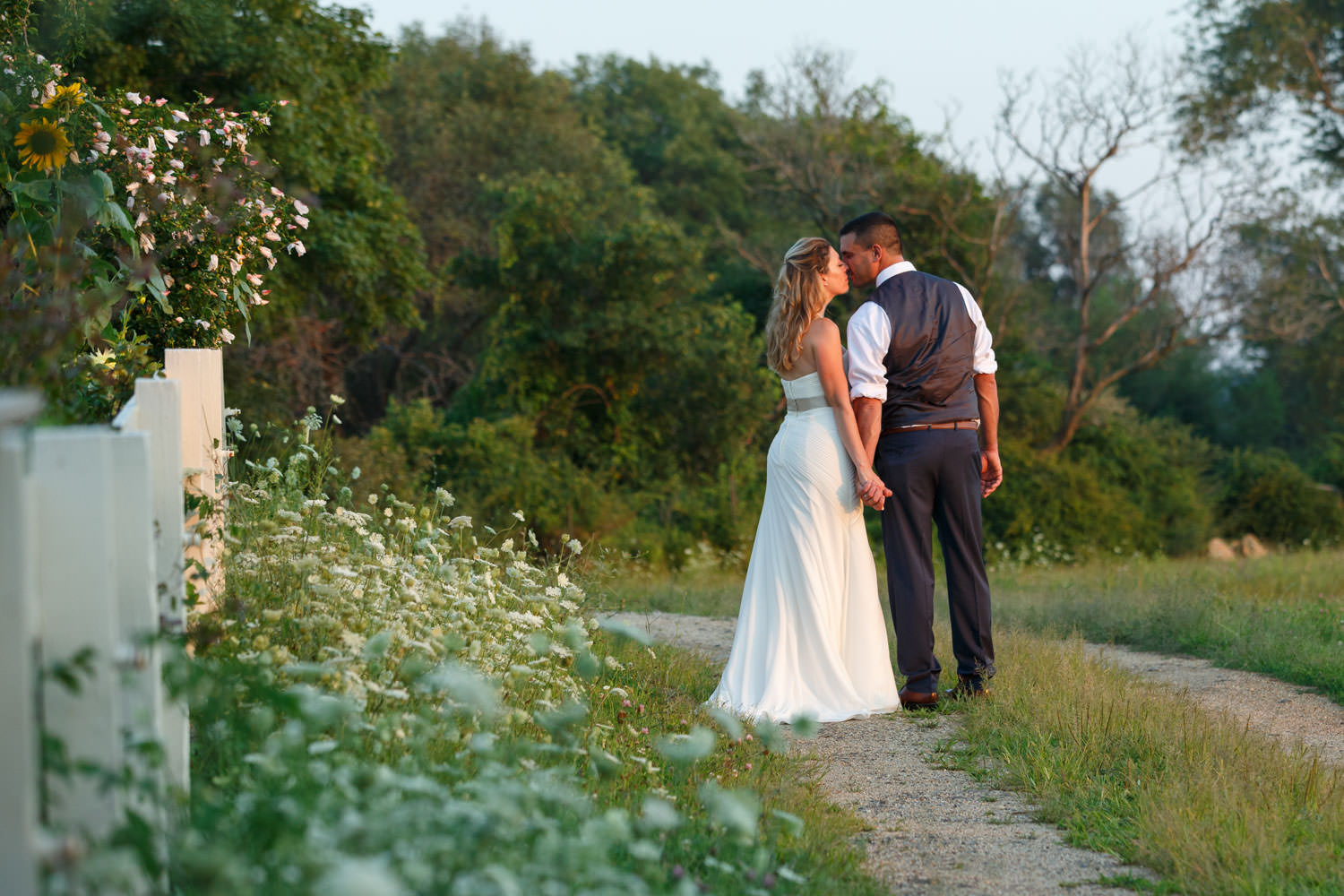Bride and Groom leaning for a kiss on path