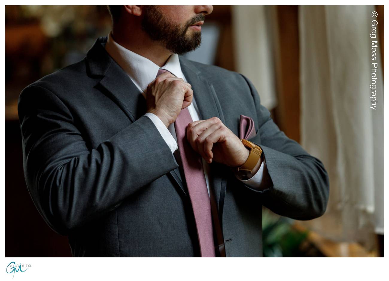 Groom adjusting maroon tie