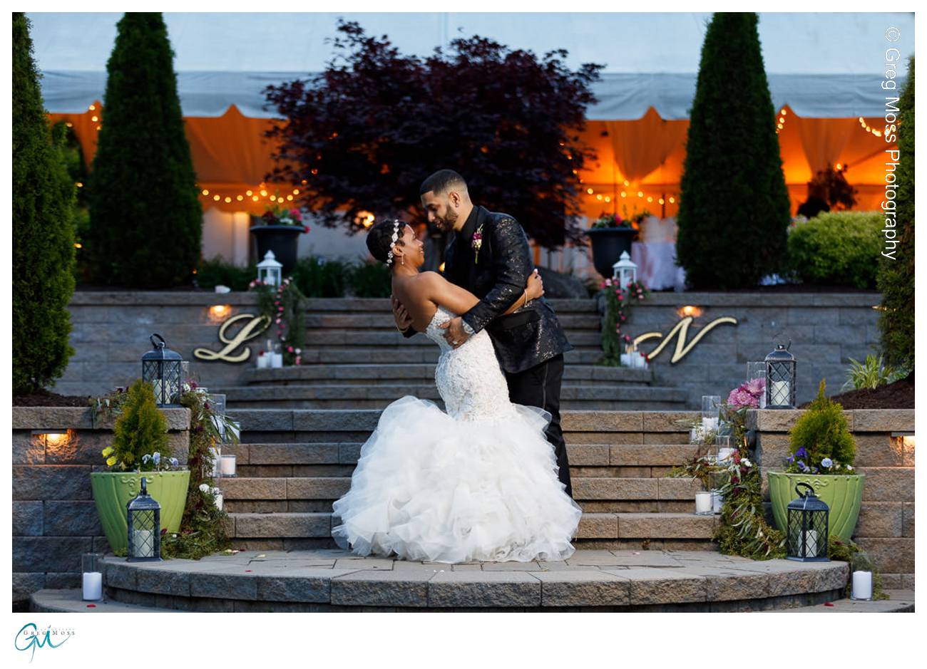Bride and groom dipping on stairs with tent in background