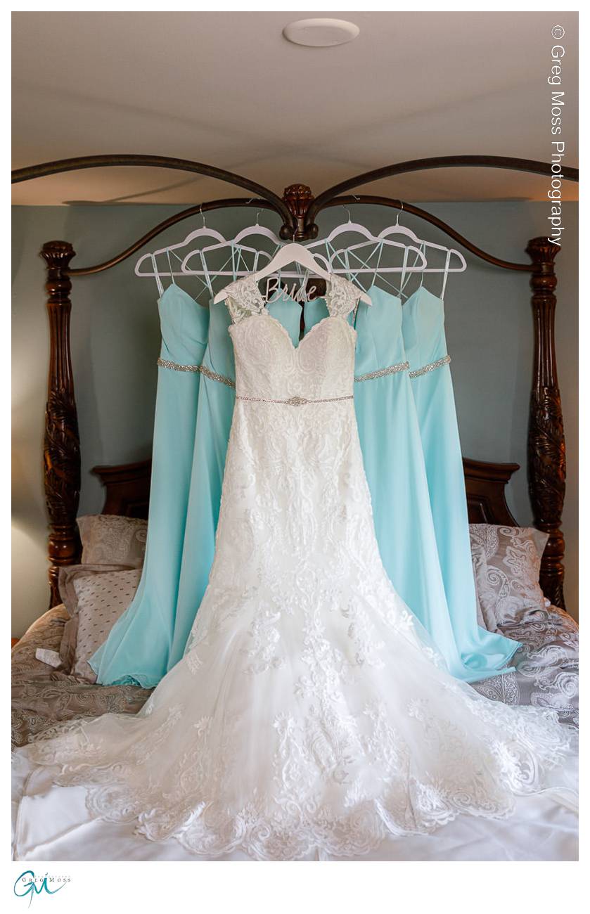 Brides dress and bridesmaids dresses hanging from four post bed