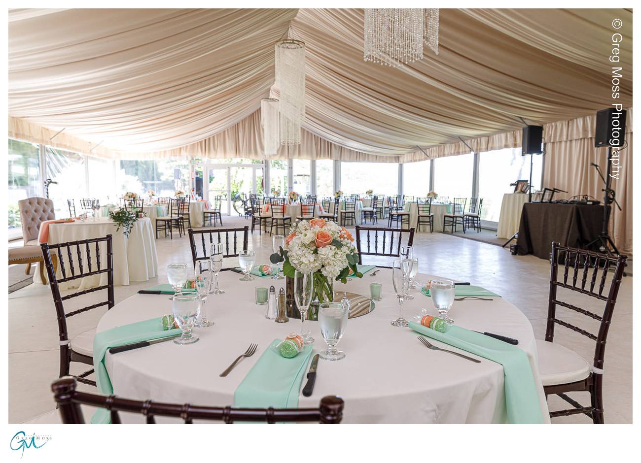 Photo inside tent with tables set with flower centerpieces and mint colored napkins