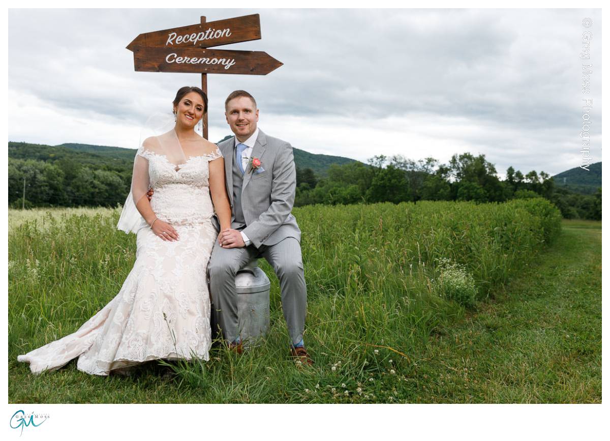 Red Barn Wedding0538 Bride and groom sitting under reception and ceremony signs