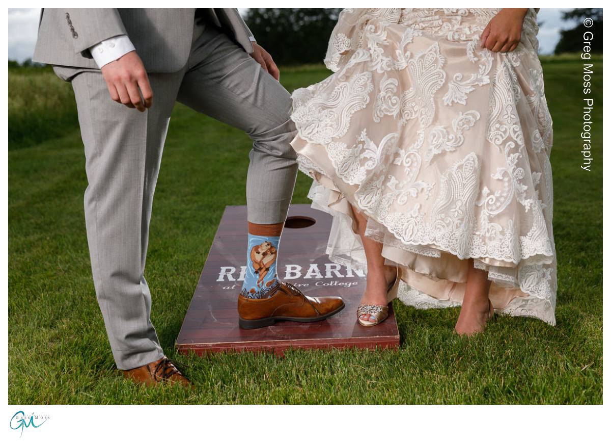 Red Barn Wedding0540 Bride and groom standing on a wooden "red barn" sign, revealing cowboy boots under their wedding attire.