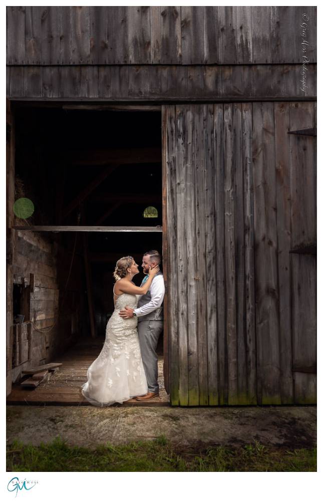 Bride and Groom leaning against barn.