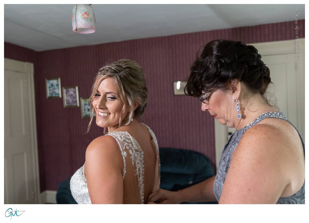 Mother of the bride helping zip up the wedding dress.