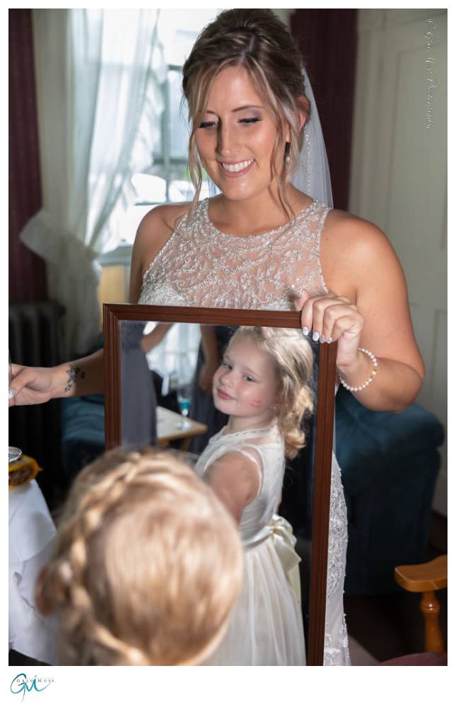 Bride with flower girl looking into mirror.