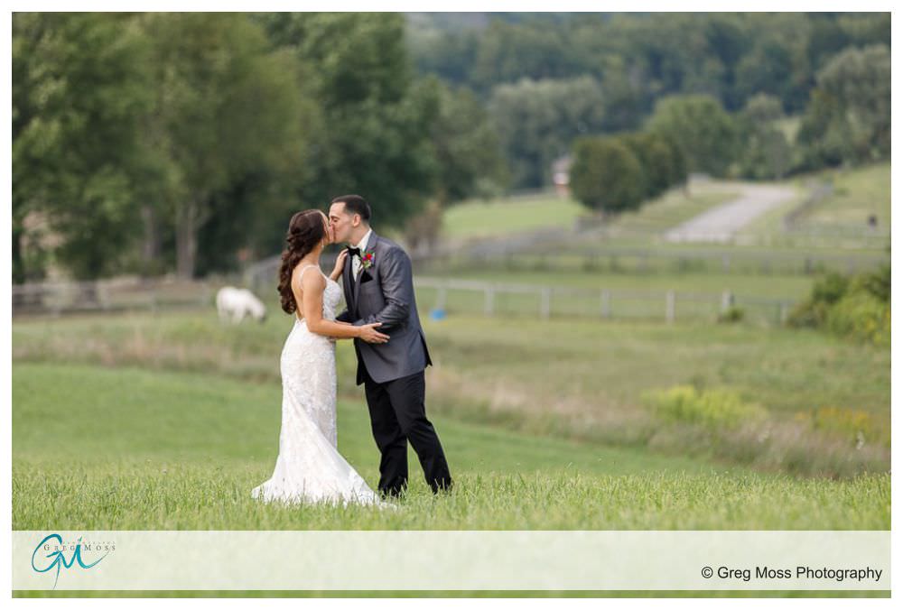wedding day portrait of bride in groom in field with pastures in background