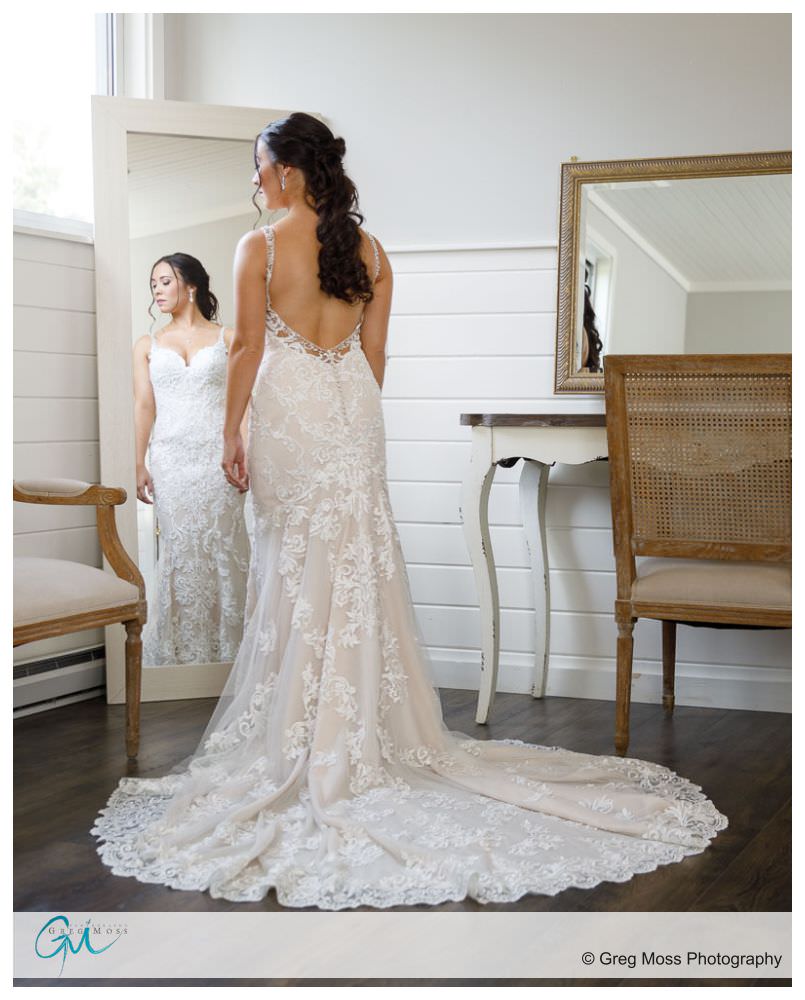 Full length photo of bride in wedding dress looking into mirror