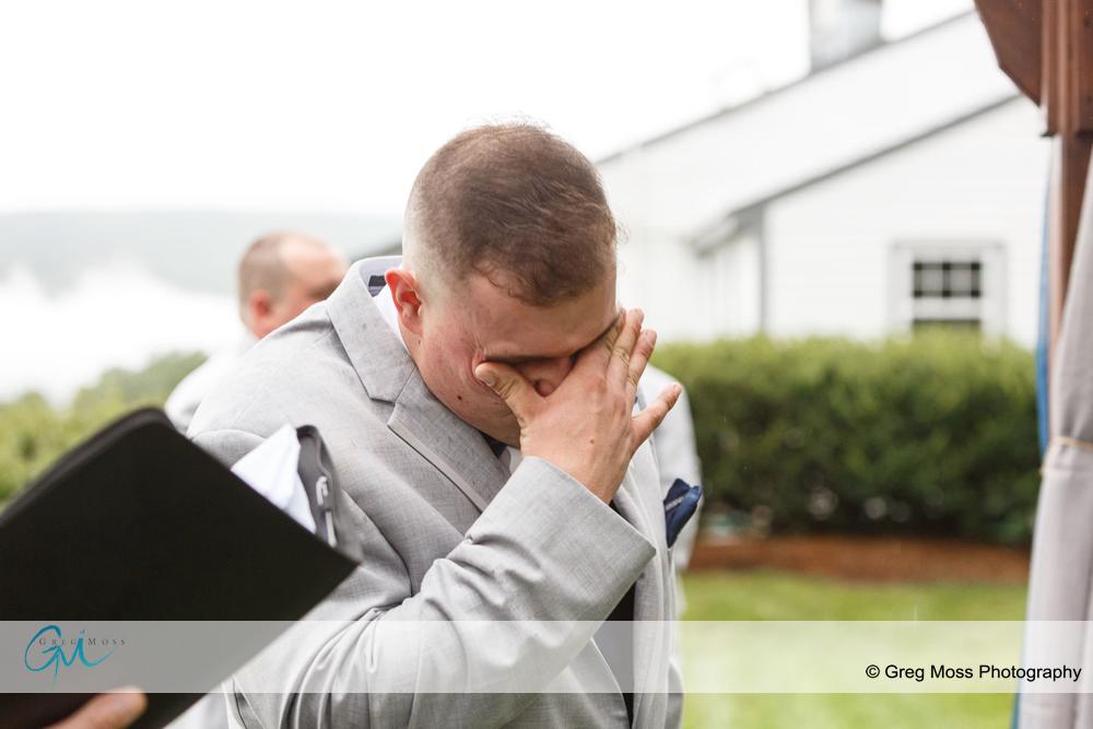 Groom tearing up while bride walks down the aisle.