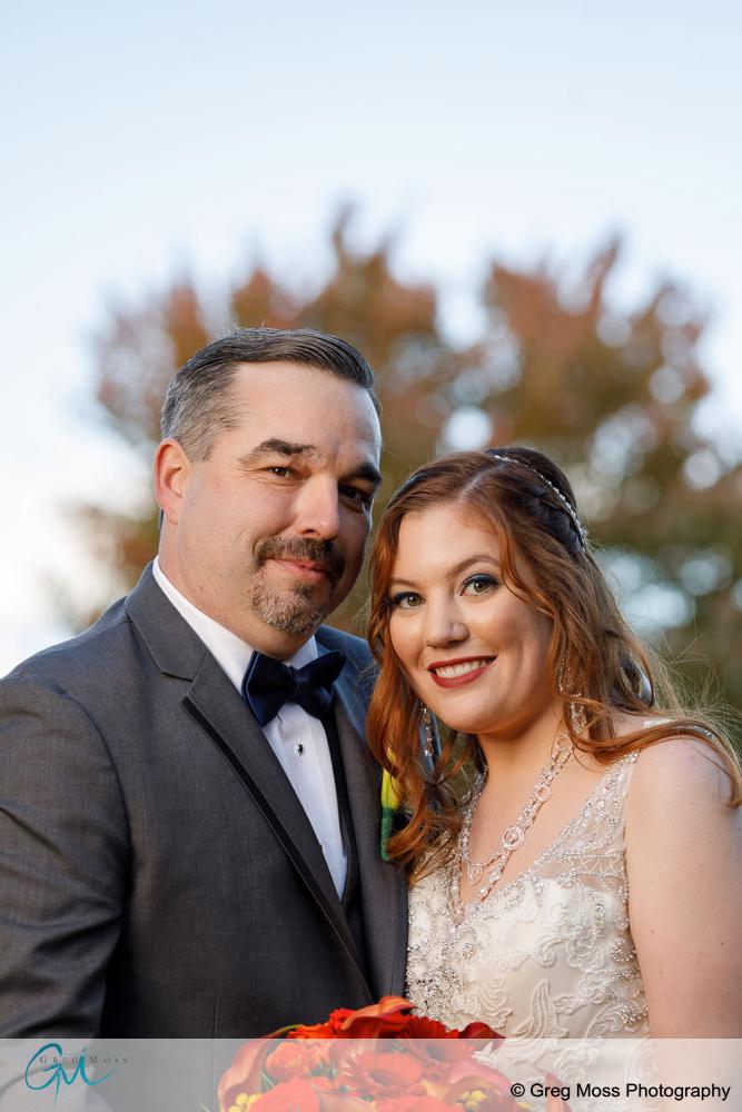 Bride and groom photo with fall foliage behind them