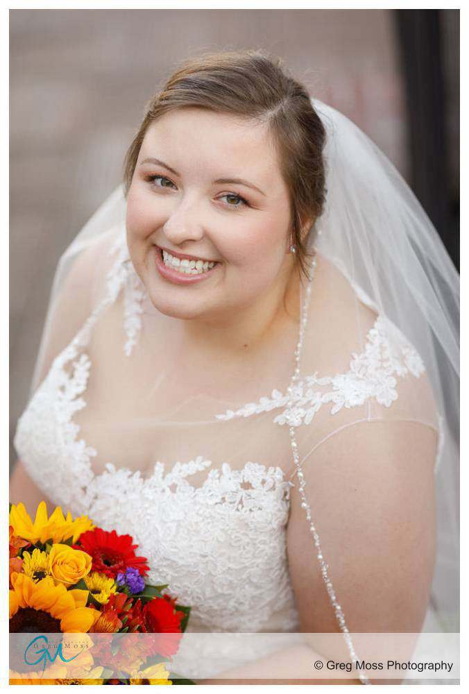 Bride by fireplace looking up while holding bridal bouquet