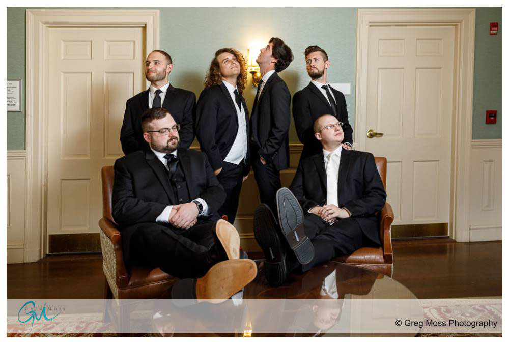 Groom and groomsmen posed on chairs outside of graves room at Inn on Boltwood