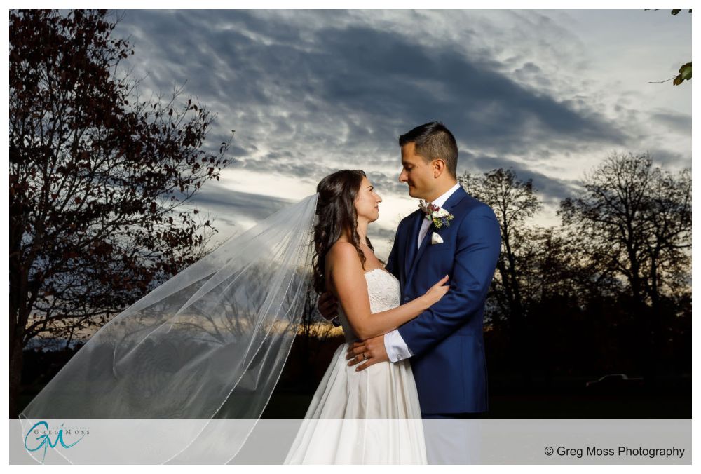 Bride and Groom portrait with veil flowing in the wind and dramatic sky in the background