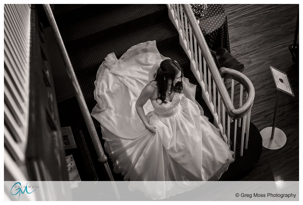 Bride walking down stairs holding wedding dress on her way to the first look