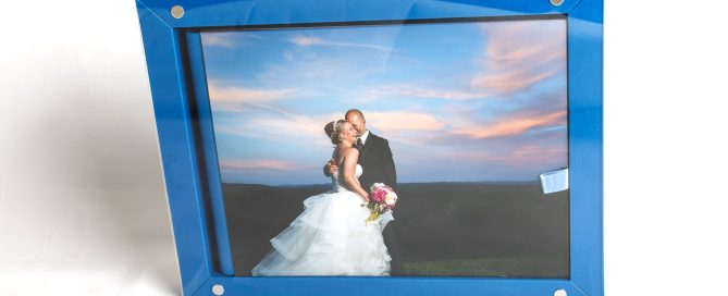 A wedding photo of a smiling couple embraced, displayed in a large blue frame against a white background, ready to be included in the album design process.