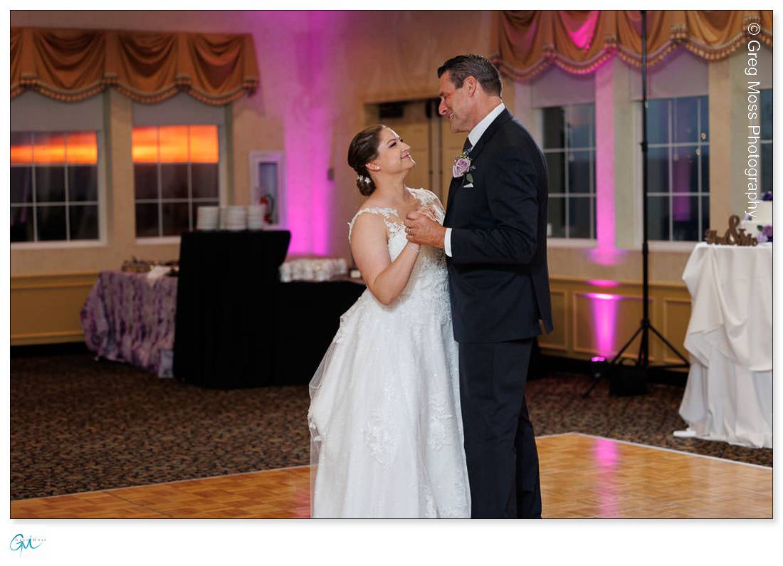 Holyoke Wedding Photography-18 Bride and groom share a dance in a Holyoke ballroom, smiling at each other; elegant decor and a reception table in the background.
