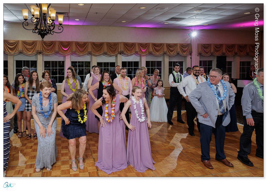 Holyoke Wedding Photography-21 Guests in Hawaiian-themed attire participate in a lively dance at a Holyoke wedding celebration, with colorful leis and joyful expressions.