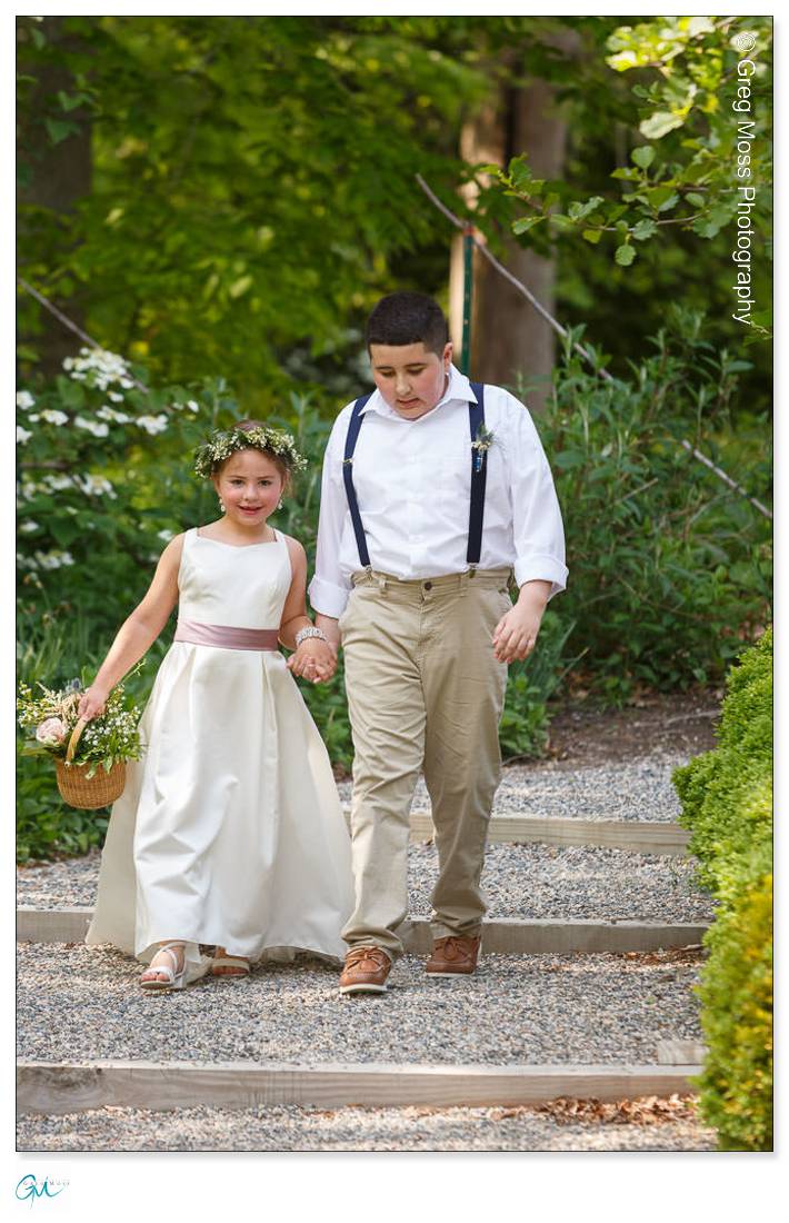 Highfield Hall Wedding-13 A young boy and girl dressed in formal wear, holding hands and walking down a Highfield Hall garden path, the girl carrying a basket.