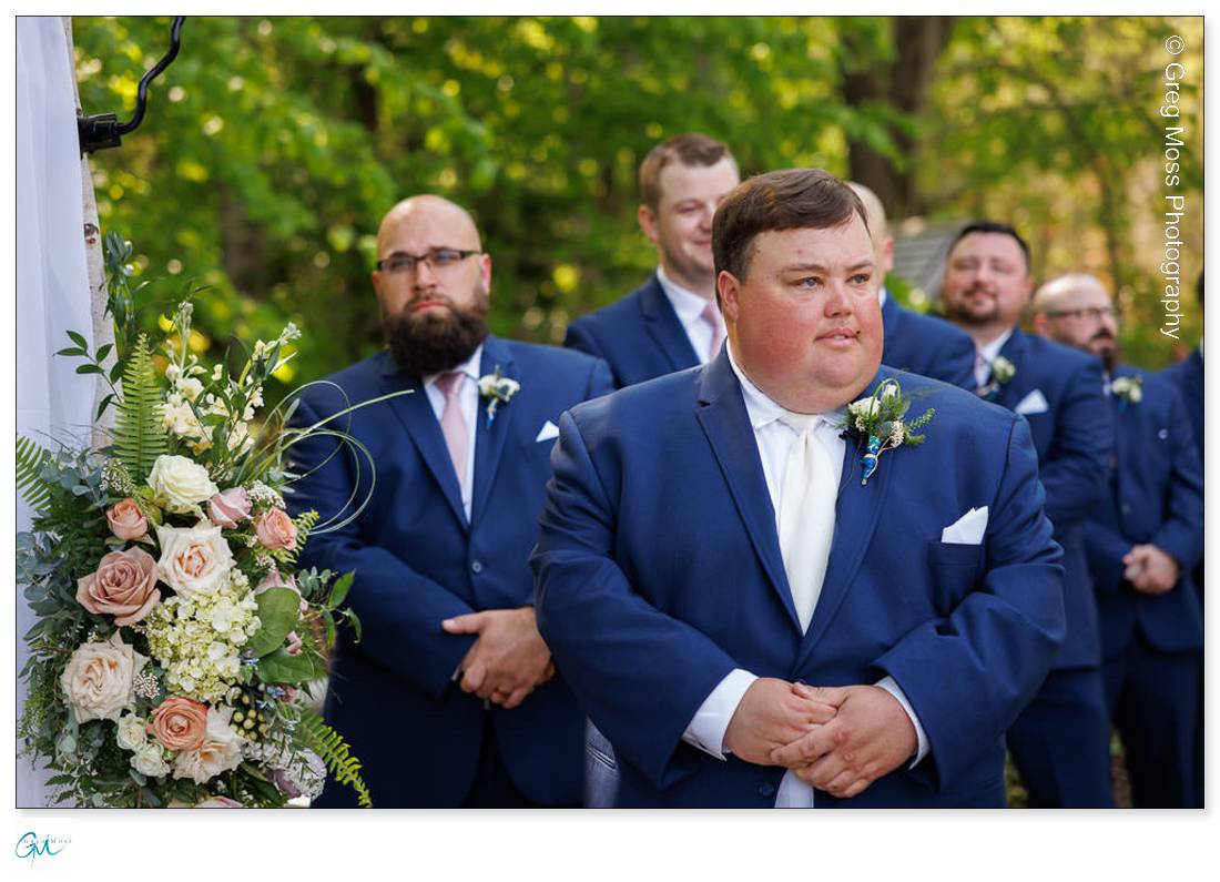 Highfield Hall Wedding-16 An emotional groom and his groomsmen during a Highfield Hall wedding ceremony outdoors, standing near floral decorations.