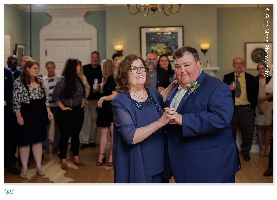 Highfield Hall Wedding-27 A man and a woman exchange rings in front of guests at a Highfield Hall wedding ceremony inside an elegant room.