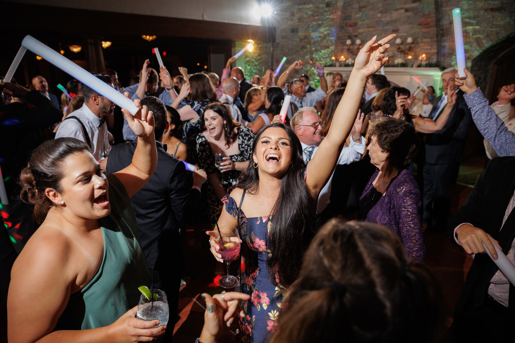 LA3_1045-1 Guests dancing and celebrating with glowing sticks at a lively indoor wedding party.
