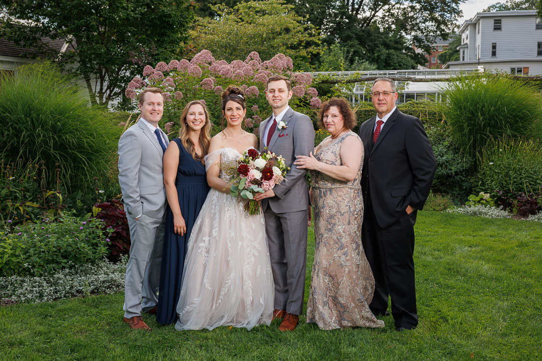 Union Station Wedding-8 Briana and Jacob, including a newlywed couple and four guests, pose in a lush garden, smiling at the camera.