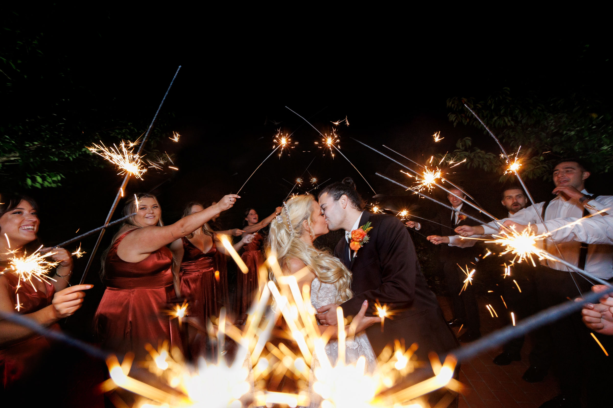 Bride and Groom with wedding party surrounded by sparklers