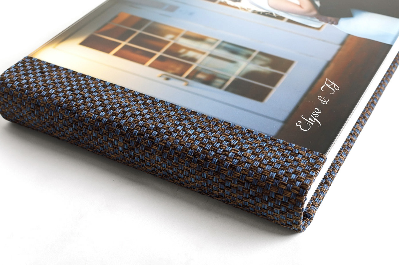A digital photo frame with a woven blue and brown border displaying a slideshow of wedding album designs on a white surface.