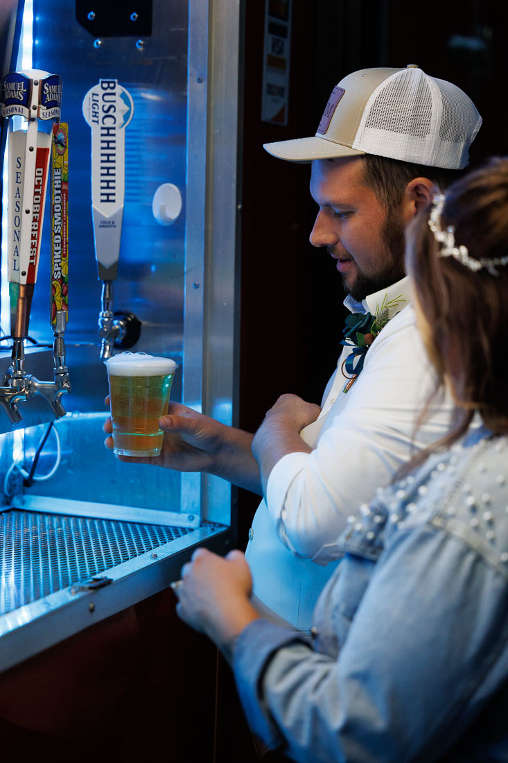 Bliss Farm Wedding-24 At the bar, a man pours a glass of beer from a tap while his friend, reminiscent of a guest enjoying Crestview Country Club wedding photos, looks on with interest.