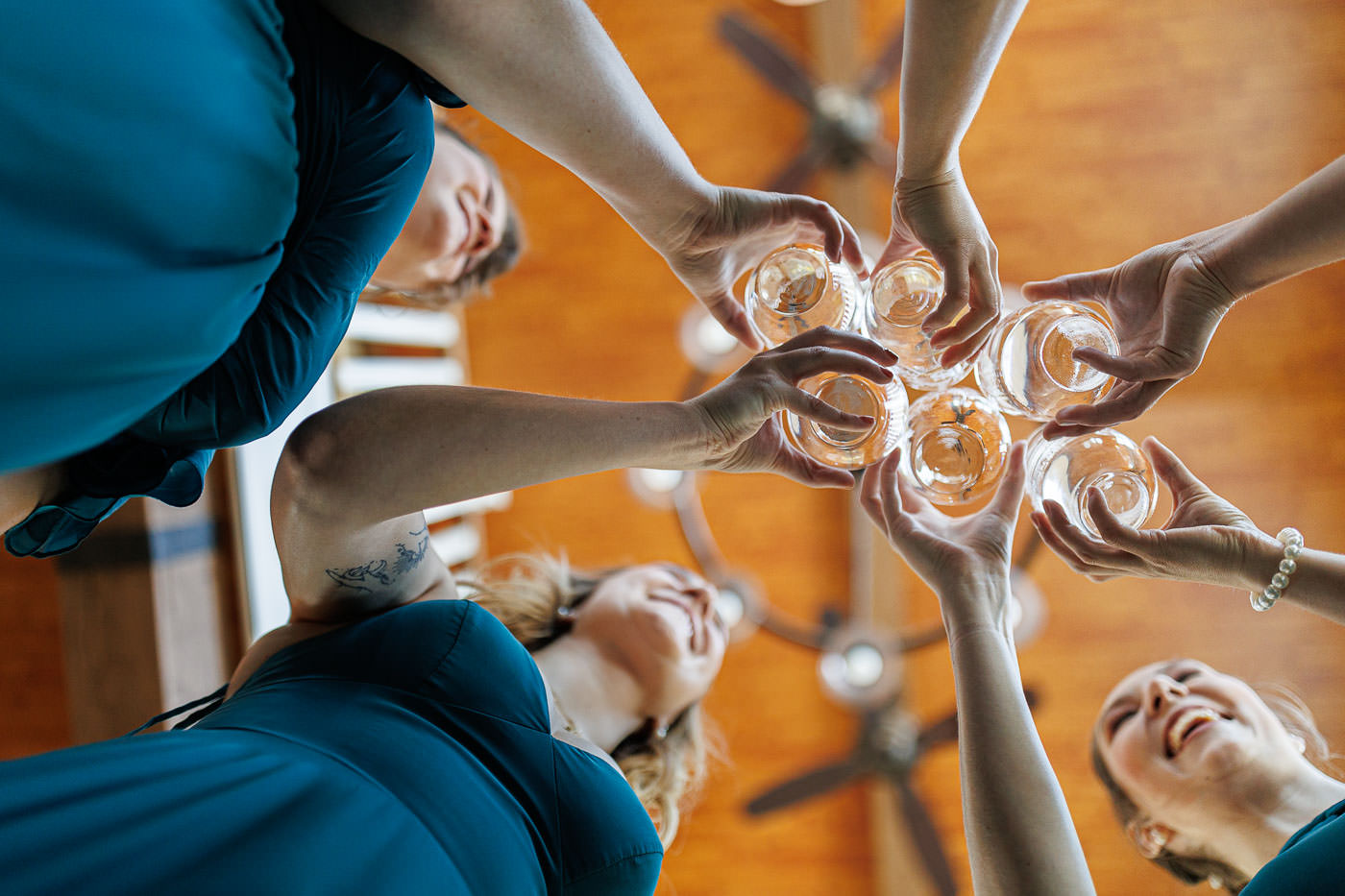 Lake house guest cottages wedding-2 Four people raising glasses in a toast, viewed from below with a wooden ceiling above, capturing the essence of joy and togetherness often found in blissful farm wedding photos.