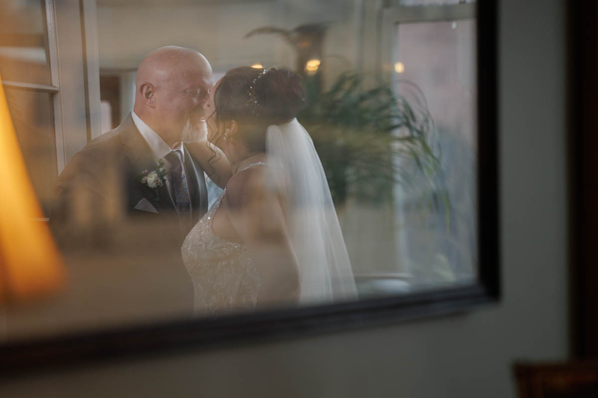 Hotel Northampton Wedding-17 At their enchanting Northampton Hotel wedding, the bride and groom share a tender kiss, beautifully framed by the window.