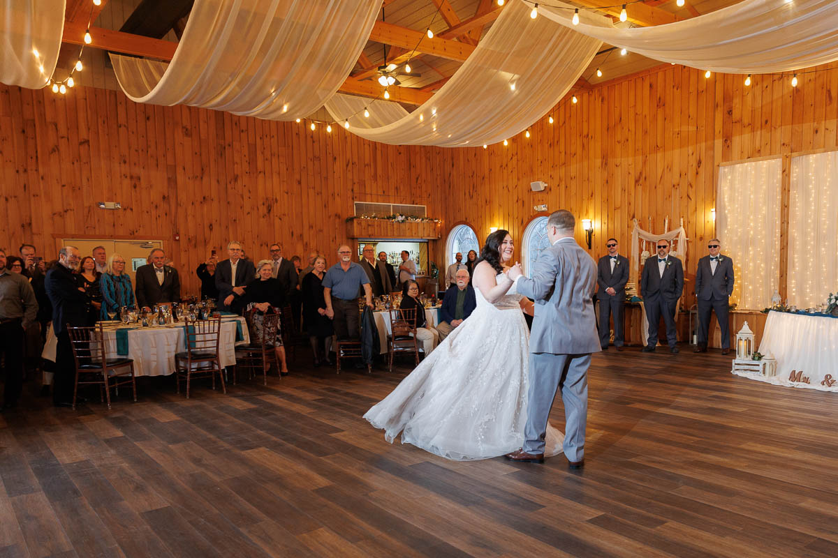 Maneeley’s banquet wedding-21 In the warmly lit wooden hall of Maneeley's, a bride and groom share a dance beneath draped ceilings. As their friends smile and watch, the charm of winter wedding photos captures every precious moment.