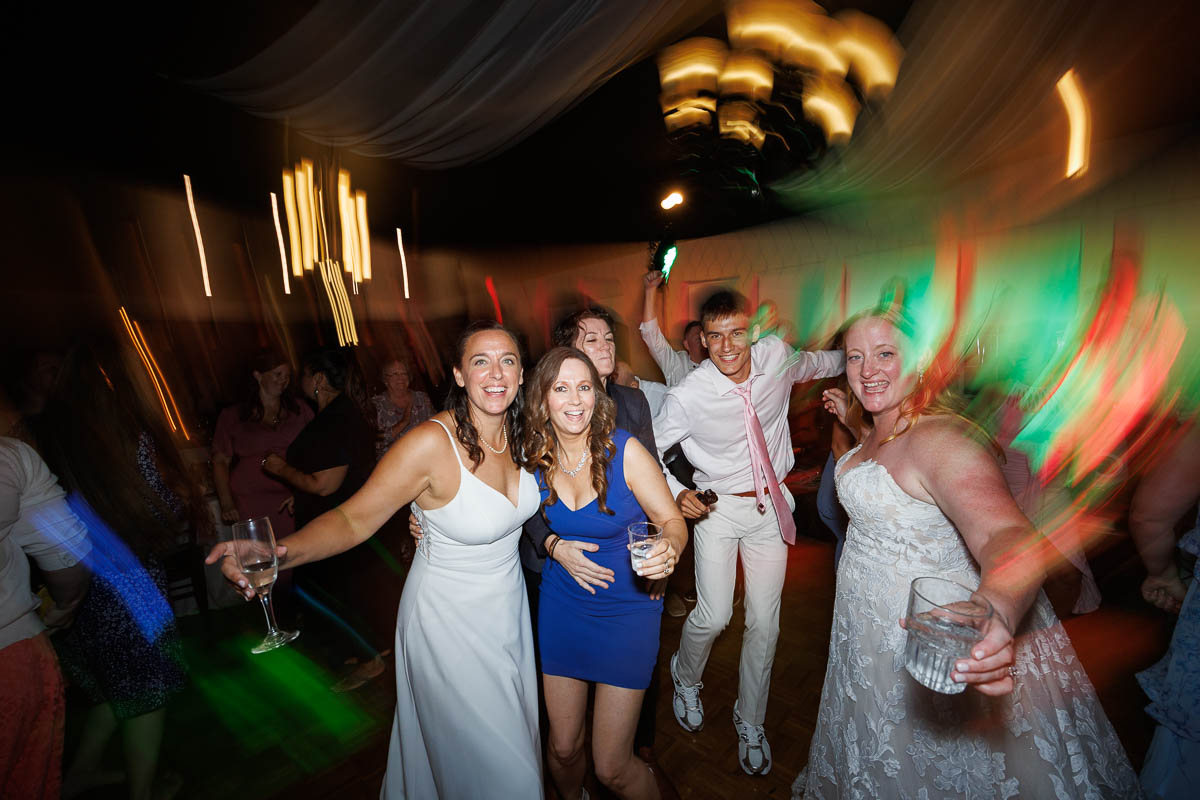 A group of people poses and smiles on a dance floor at a party at The Log Cabin Holyoke, with colorful lights and motion blur creating a lively atmosphere captured perfectly in this photo and video.