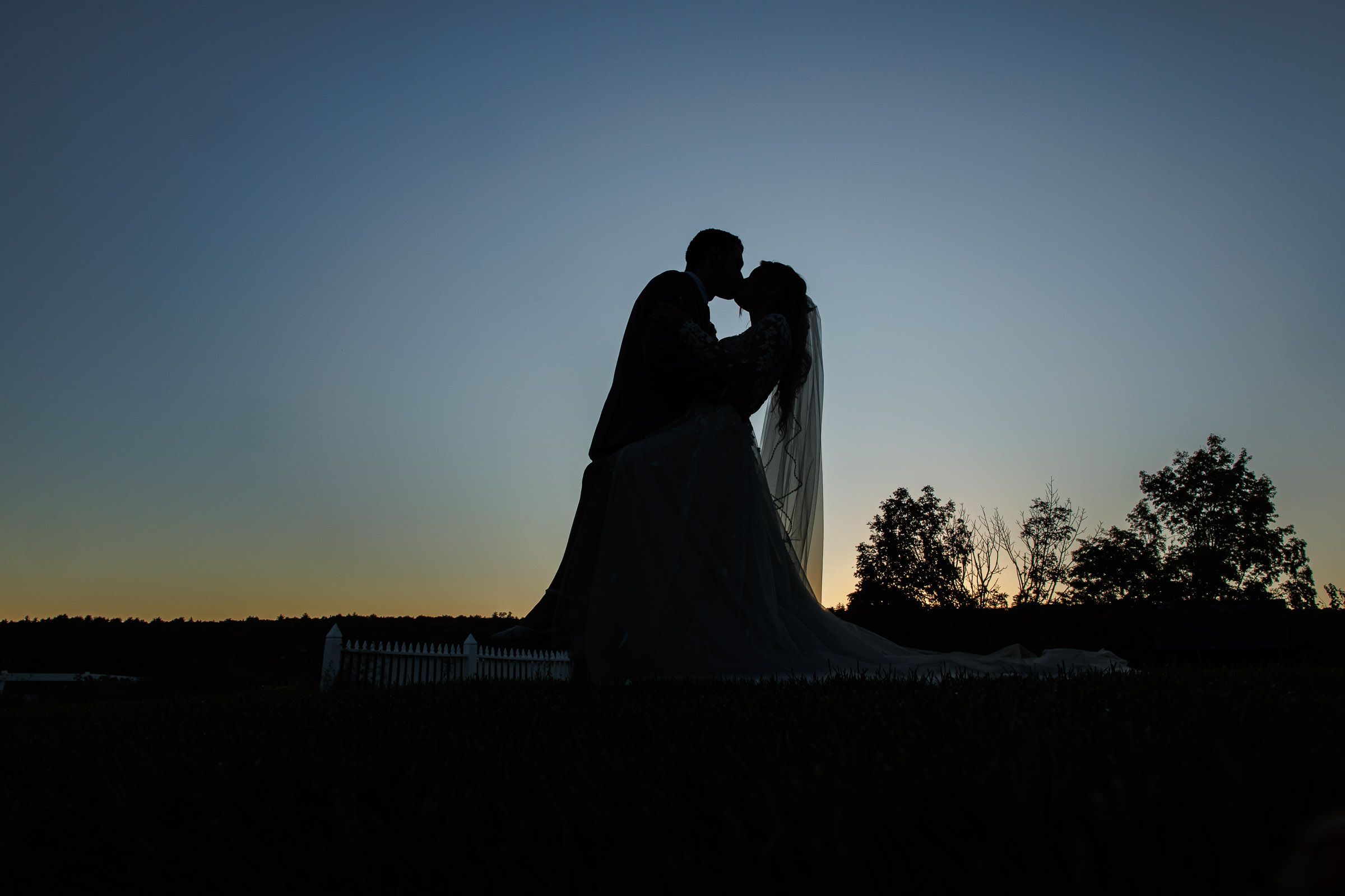 Silhouette of a bride and groom kissing at sunset, captured in this fall wedding photography.